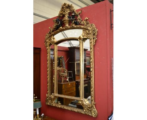 A gilt framed wall mirror, an arrangement of five mirrors, the frame surmounted by seated cherubs, urn and flora. 