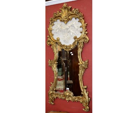 A gilt framed wall mirror, heart shaped plaque cast with putti in relief over shaped glass, the frame with C-scroll flora.