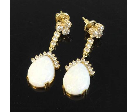 A pair of yellow metal opal and diamond drop earrings each featuring a pear cut opal cabochon with 9 round brilliant cut diam