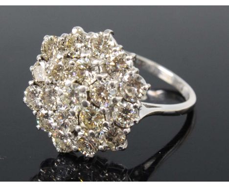 An 18ct white gold diamond circular cluster ring, comprising 19 round brilliant cut diamonds in tiered claw settings, diamond