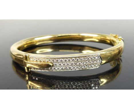 A yellow metal diamond oval hinged bangle, comprising a centre buckle section in white pavé set with 51 melee cut diamonds, w
