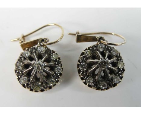 A pair of yellow and white metal diamond circular cluster earrings each featuring 9 old European cut diamonds in claw setting