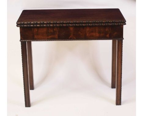 An Edwardian mahogany card table in the Georgian style, the fold-over top with egg and dart moulded frieze, opening to reveal