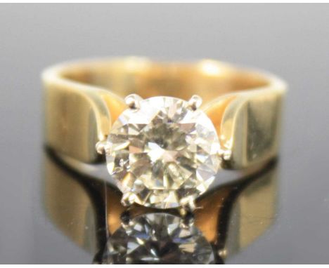 A yellow metal diamond solitaire ring, comprising a round brilliant cut diamond in a six-claw setting, with tapered shoulders