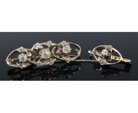 Two yellow and white metal diamond bar brooches, the larger featuring three graduated old cushion cut diamonds within a scrol