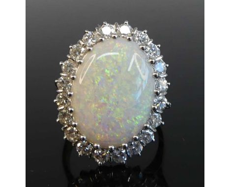 An 18ct yellow and white gold opal and diamond oval cluster ring featuring a centre opal cabochon within a border of 20 round