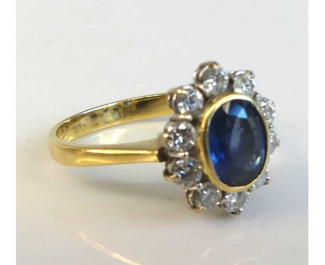 An 18ct yellow and white gold sapphire and diamond oval cluster ring comprising a centre sapphire within a border of 10 round