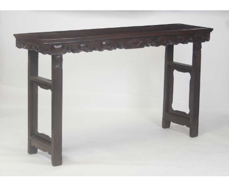 An early 20th century Chinese rosewood altar table, having a carved frieze and raised on square cut end supports, w.179cm, d.