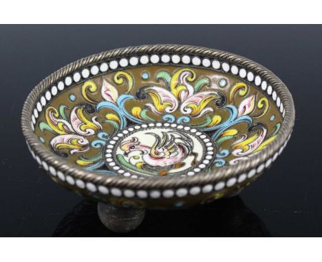A white metal and enamel footed small bowl, probably Russian, decorated in bright enamel with flowers and foliage, raised on 