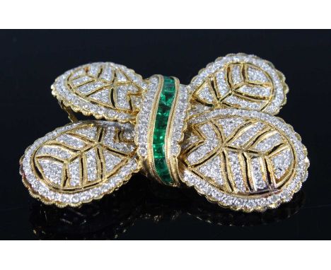 A yellow metal diamond and emerald stylised bow brooch, comprising 203 1.15mm melee cut diamonds in pavé settings and a centr