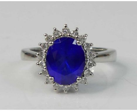 A platinum tanzanite and diamond oval cluster ring, featuring an oval tanzanite within a border of 18 round brilliant cut dia