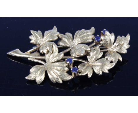 An 18ct yellow gold stylised leaf spray brooch, having four 2.25mm round sapphire accents and a roller catch fastening, sapph