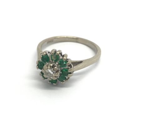 An 18carat gold ring set with a central brilliant cut diamond flanked by emeralds ring size M-N