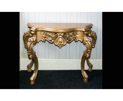 A Reproduction Rococo Style Console Table Pale gilt table with moulded curlicue form apron and legs. Height, 31 inches, lengt