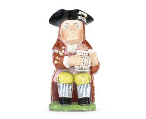 A rare enamelled electioneering 'Reform' Toby Jug, circa 1831Of traditional form, seated and wearing a black tricorn hat rese