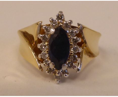 A 14ct gold ring, set with a sapphire and diamond, surrounded by small claw set diamonds 