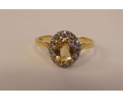 An 18ct bi-coloured gold ring, set with a central yellow stone, surrounded by small diamonds 