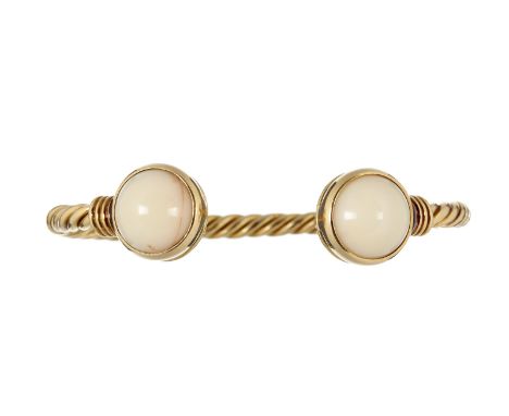 A white coral torque bangle, the white coral cabochon terminals rub over set on a twisted yellow gold coloured bangle, unmark
