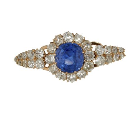 A late 19th century sapphire and diamond brooch, the central oval mixed cut sapphire claw set above a surround of cushion sha