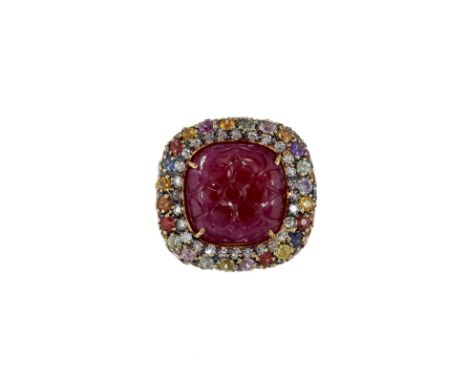 A carved ruby and multi gem set ring, the central cushion shaped ruby carved with a flower, claw set within a surround of cir