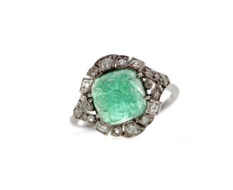 CARVED EMERALD AND DIAMOND RING, the cabochon cushion shaped emerald carved to depict a central flower amongst a bed of leave