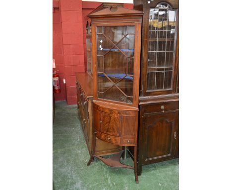 An Edwardian mahogany corner cupboard, architectural pediment, astragal glazed door to top, projecting bow front base, single