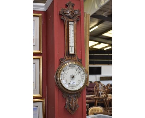 A late Victorian carved oak wheel barometer, aneroid barometer with thermometer