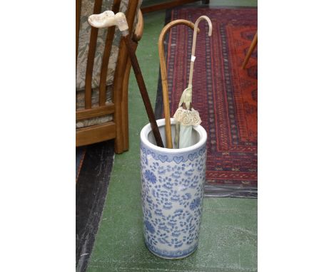 A large blue and white ceramic stick stand decorated with flowers;  a walking stick; a parasol etc (4)