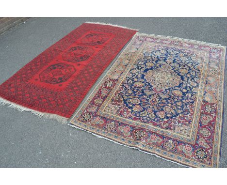 A hand woven Middle Eastern carpet in sheds of black and red 204cm x 112cm; another Middle Eastern carpet,  intricately woven