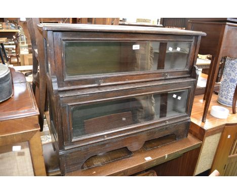 A two tier oak Globe Wernike style bookcase, projecting base, shaped apron