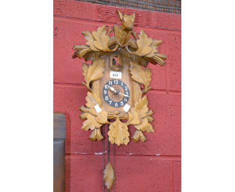 A cased wooden cuckoo clock with weights and pendulum