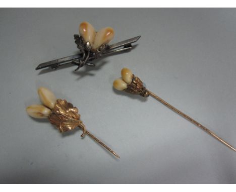 Three 19th century Continental pins set with deer teeth, all set as pairs of teeth blossoming from bunched oak leaves with or