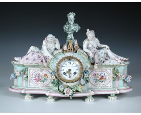 A 19th century French porcelain mantle clock, the case surmounted by two female figures flanking a male bust and symbols of p