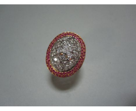 A diamond and ruby dress ring, designed as a geometrically pierced oval set with round brilliant cut diamonds in a double bor