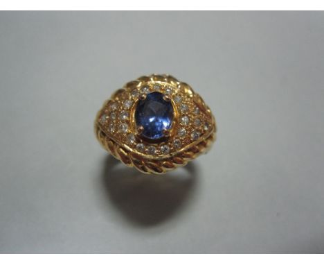 A Sri Lankan sapphire and diamond ring, the oval cut light indigo coloured sapphire claw set above a textured marquise shaped