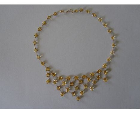A citrine bib necklace, designed as a line of spectacle set oval and round cut light golden citrines suspending from the fron