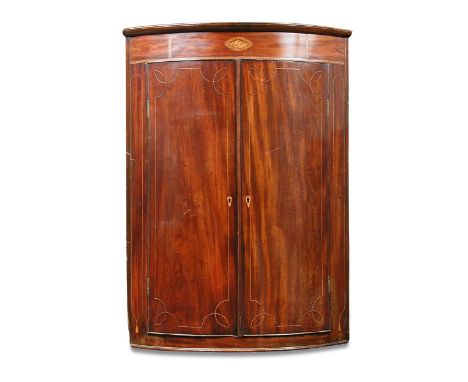 A George IV mahogany bow front corner cupboard, with conch shell inlaid frieze and line inlaid border decoration 108 x 77cm (