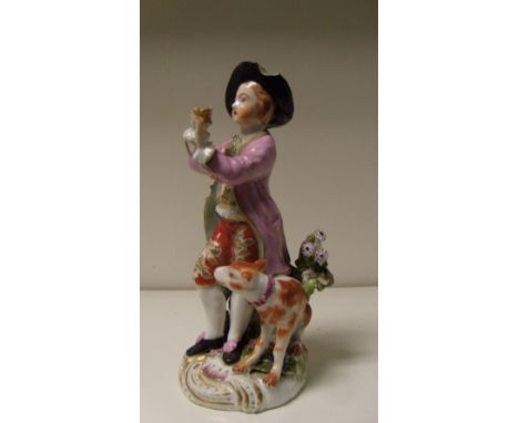A patch marked Derby figure of a clarinettist standing amongst flowers on a rococo base, his brown and white dog seated to on