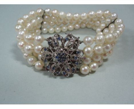 A four row pearl bracelet with sapphire set feature clasp, the uniform 6mm pearls with two bar spacers and a full width flowe