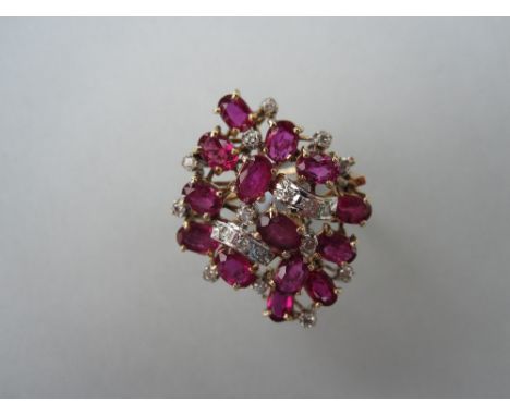 A modern ruby and diamond cluster ring, designed as a pierced and seemingly random pile of oval cut rubies and round brillian