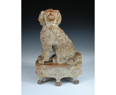 Attributed to Brampton, a brown saltglaze spaniel seated on a plinth sprigged with sheep and cornucopiae of flowers above six