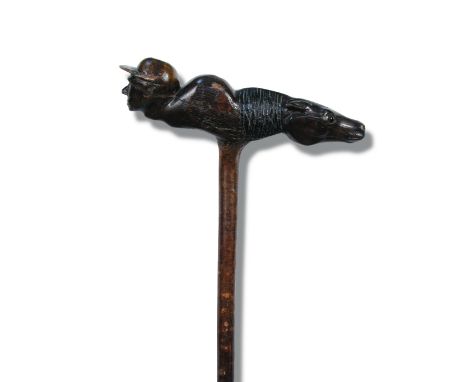 An unusal carved wood walking stick, the handle carved with the head of a jockey to one side and the head of a horse to the o