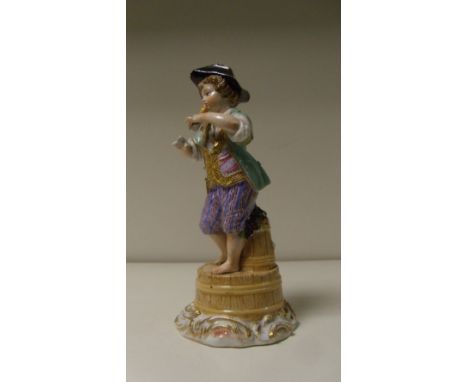 A Meissen figure of a clarinettist, he stands barefooted on an upturned tub with grapes on another behind him and on his blac