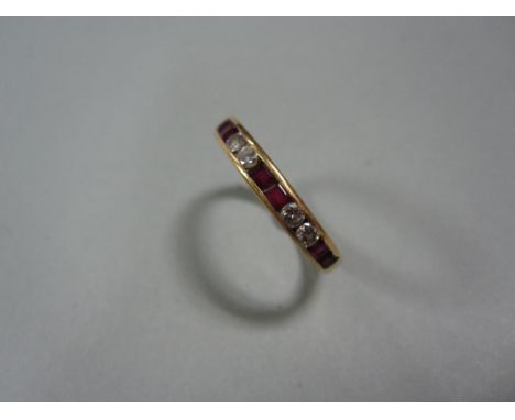 A ruby and diamond half-hoop ring in 18ct gold, channel set with pairs of calibré cut rubies alternating with pairs of round 