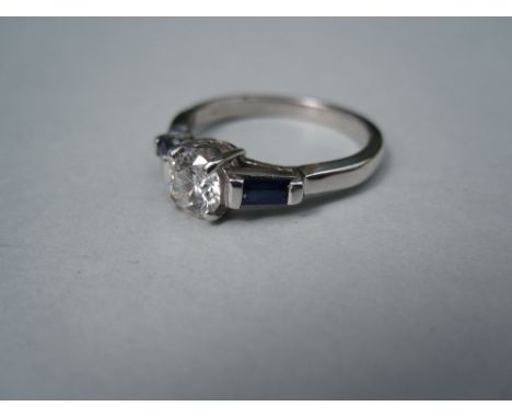 A contemporary diamond and sapphire ring, the round brilliant cut diamond, estimated weight 0.44cts set between baguette cut 