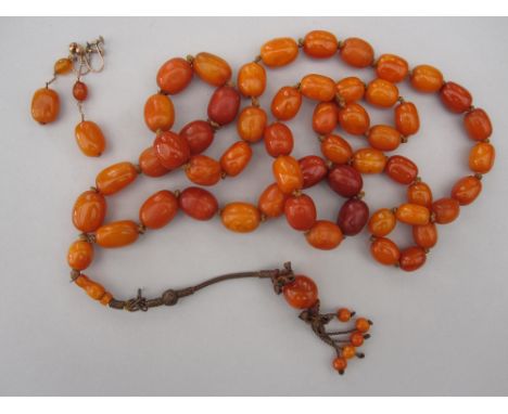 A vintage butterscotch amber tassel necklace and pair of matched earrings, the long rope of graduated oval amber beads of var