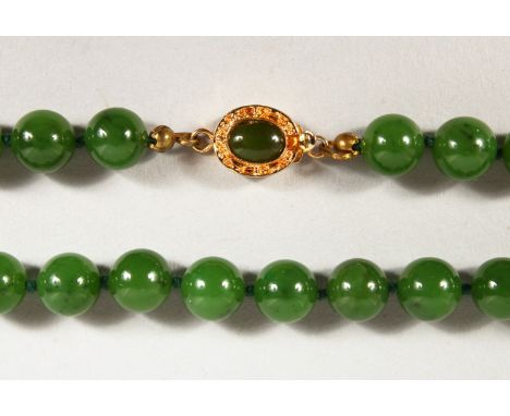 A JADE BEAD NECKLACE, with gold coloured clasp. 23ins long.