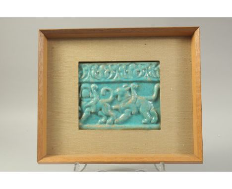 A 12TH CENTURY KASHAN TURQUOISE GLAZED POTTERY TILE, with relief decoration depicting lions/beasts, inset with a frame, tile 