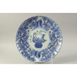 A JAPANESE ARITA PORCELAIN SCALLOP-RIM CHARGER, with central basket of flora and further