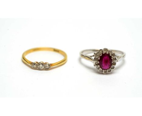 A three stone diamond ring, on gold shank stamped '18ct', ring size N; and a ruby and diamond cluster ring, the white gold sh